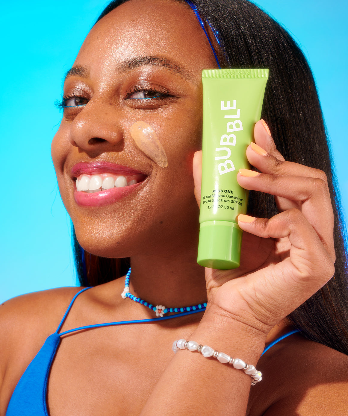 Woman applying and displaying tinted mineral sunscreen SPF 40